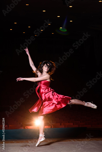 A girl in a red dress is dancing on stage. © fotofrol
