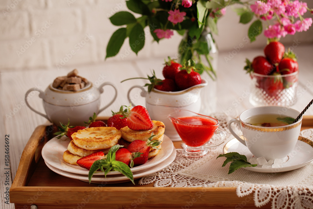 Syrniki with strawberry and green tea cup on a light background Syrniki with strawberry and green tea cup on a light background