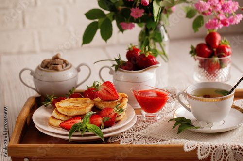 Syrniki with strawberry and green tea cup on a light background