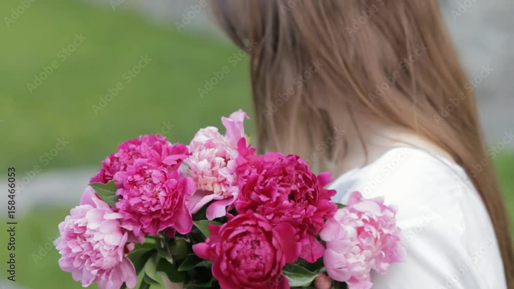 Woman makes peonies bouquet sitting in park Woman makes peonies bouquet sitting in park