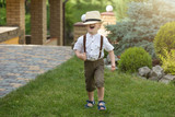  A little boy in a straw hat walks in the Park.