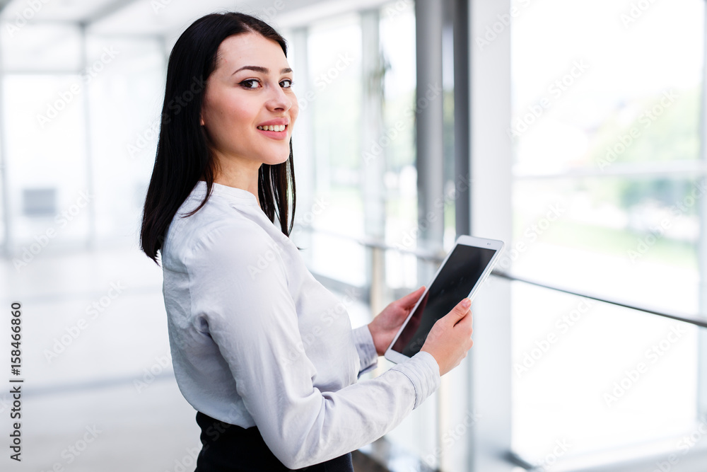 Fototapeta premium Beauitful business woman standing and looking in camera while holding tablet