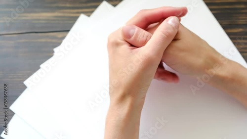 Fragment of human hands, business woman or freelancer is sitting and waiting, empty sheets of paper are on the table