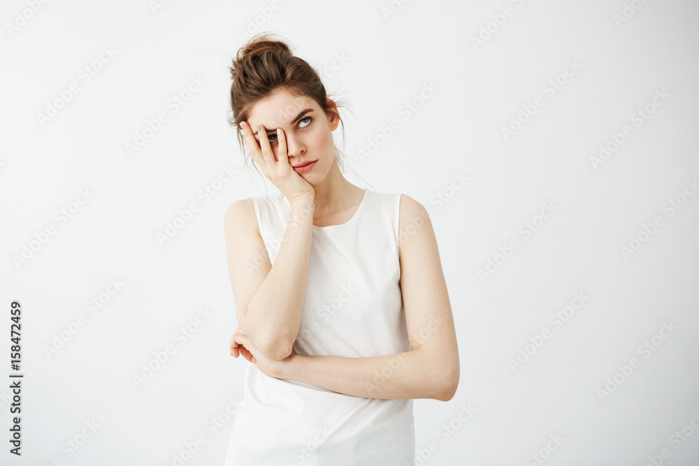 Bored tired young pretty girl hiding face behind hands over white background. Bored tired young pretty girl hiding face behind hands over white background.