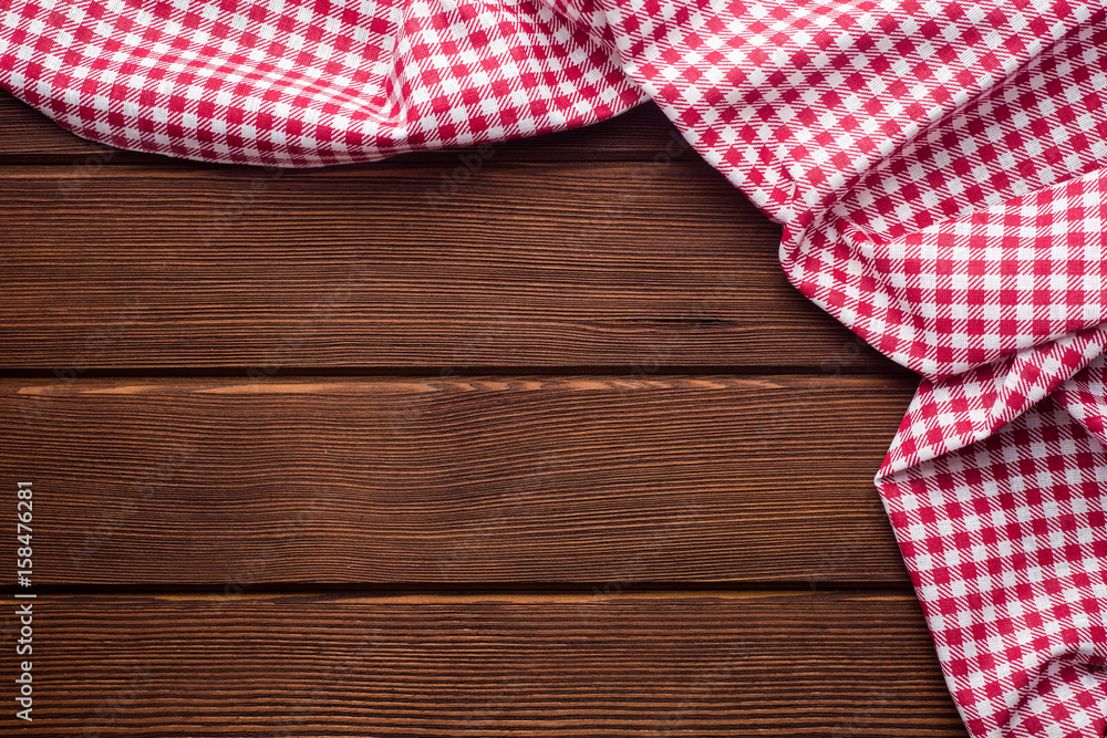 Napkin in a red and white cage on a wooden background, texture, copy space Napkin in a red and white cage on a wooden background, texture, copy space