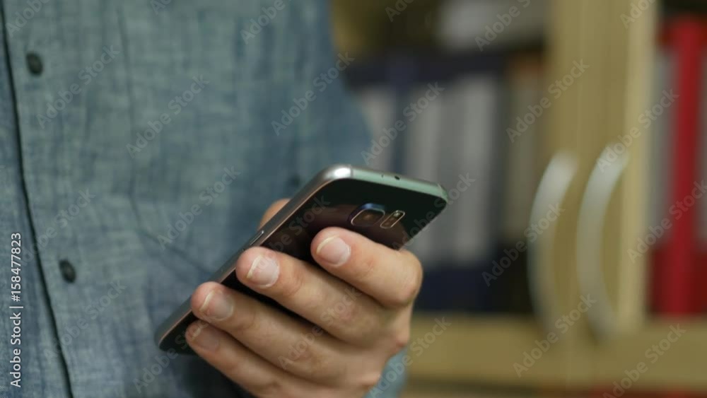 A Man In A Grey Shirt With the Mobile Phone In Hand A Man In A Grey Shirt With the Mobile Phone In Hand