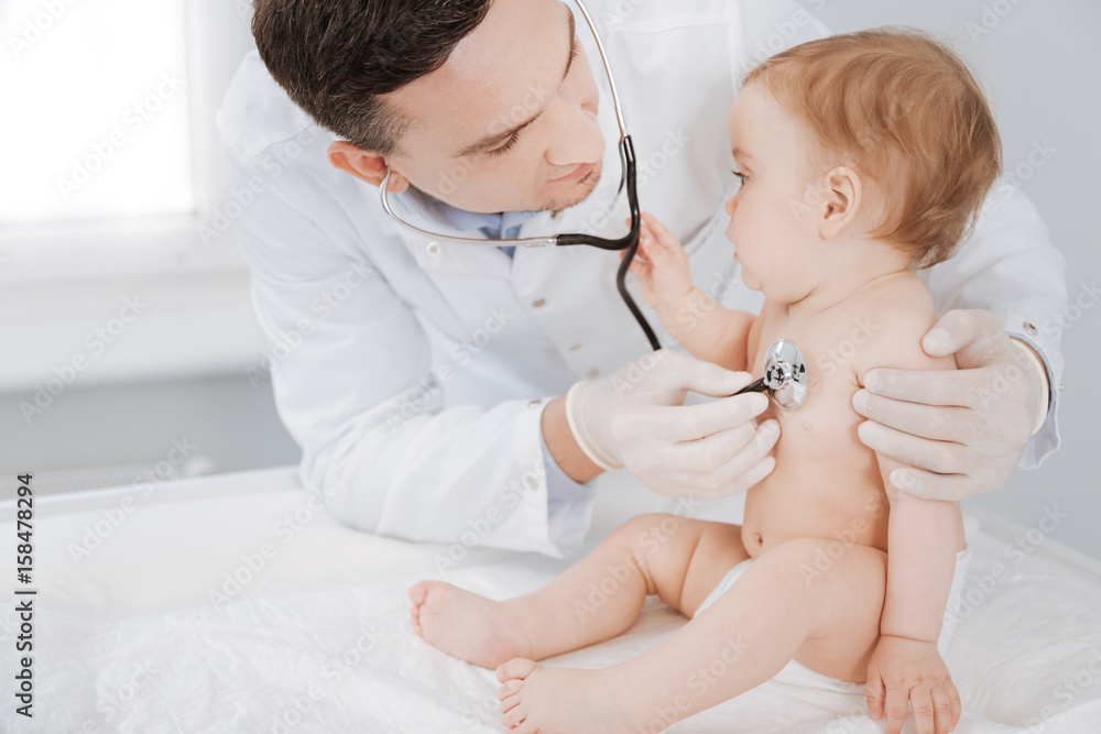 Curious lively toddler seeming interested in doctors equipment Curious lively toddler seeming interested in doctors equipment