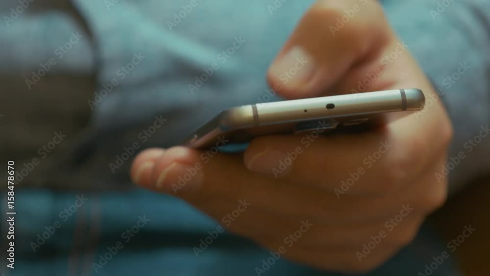 A Man In A Grey Shirt And Jeans Sitting On The Couch With the Mobile Phone In Hand A Man In A Grey Shirt And Jeans Sitting On The Couch With the Mobile Phone In Hand