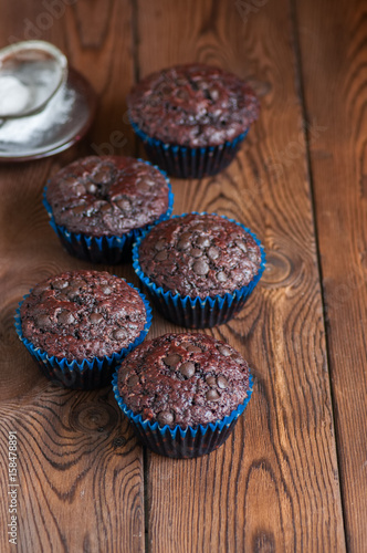 Homemade rich double chocolate muffins with chocolate chips on a wooden background. Close up and copy space.