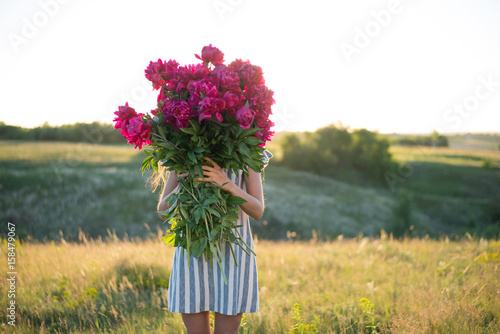 spectacular portrait of woman with big bouquet of rose peonies at sunset