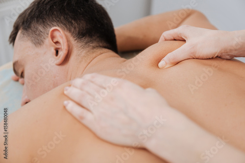 Young troubled man relaxing under specialists hands