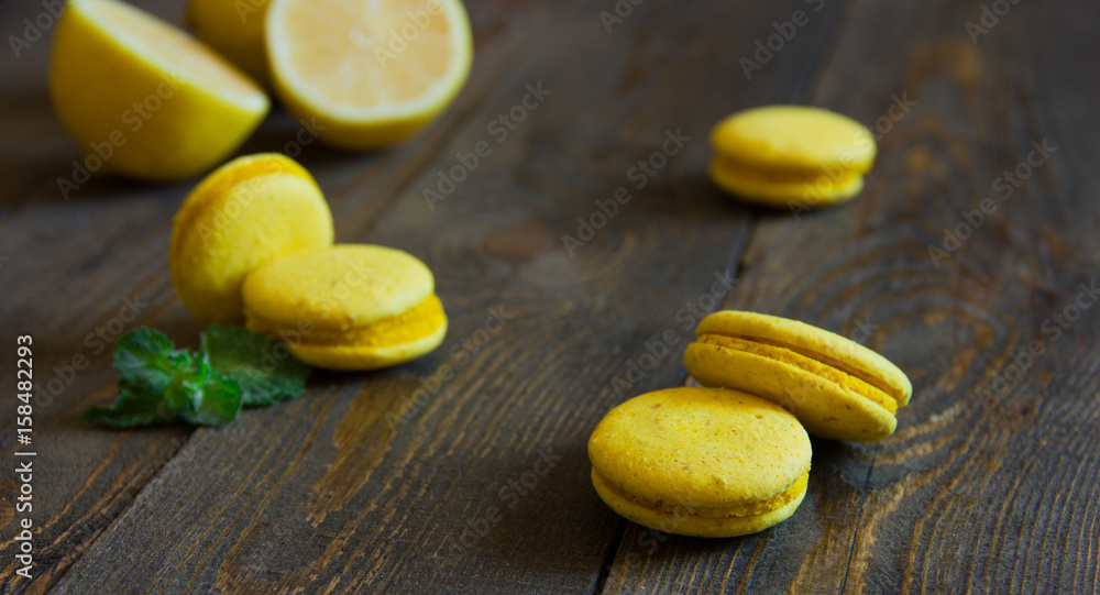 yellow macaroons with lemon on a wooden table yellow macaroons with lemon on a wooden table