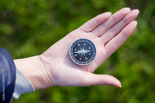 Hand holding the black compass isolated on green background