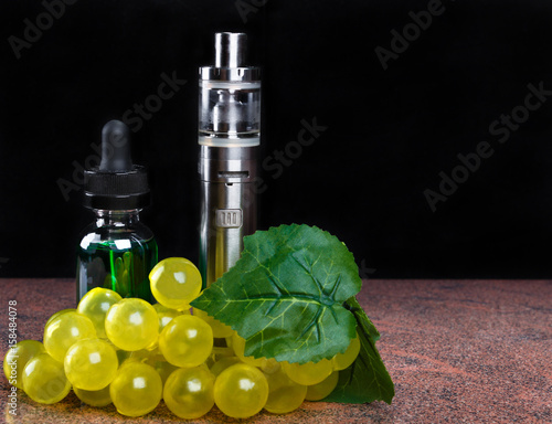 Electronic cigarette, bottle with vape liquid and bunch of grapes with leaf on black background photo