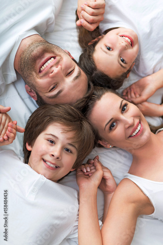 Family of four lying on bed 