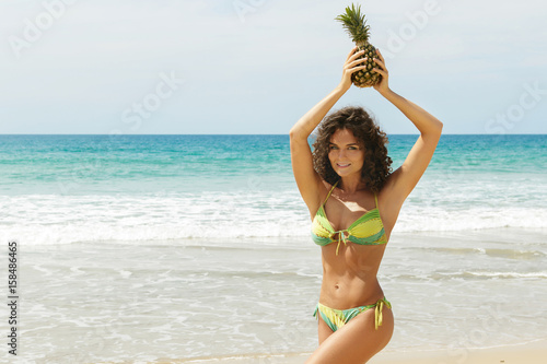 Woman with a pineapple fruit on the beach