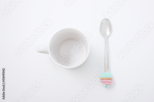 White cup with a spoon and cookies on a white background