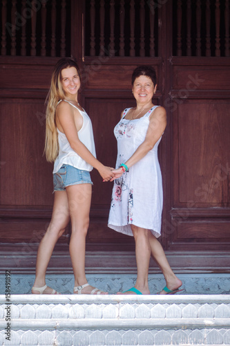 happy senior mother and adult daughter Look at camera and hold hands photo