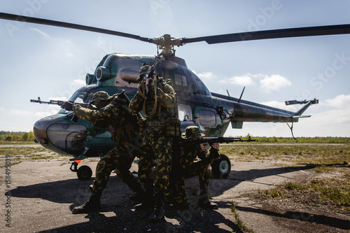 Fototapeta Naklejka Na Ścianę i Meble -  Photos of a group of military men with a gun in front of a helicopter
