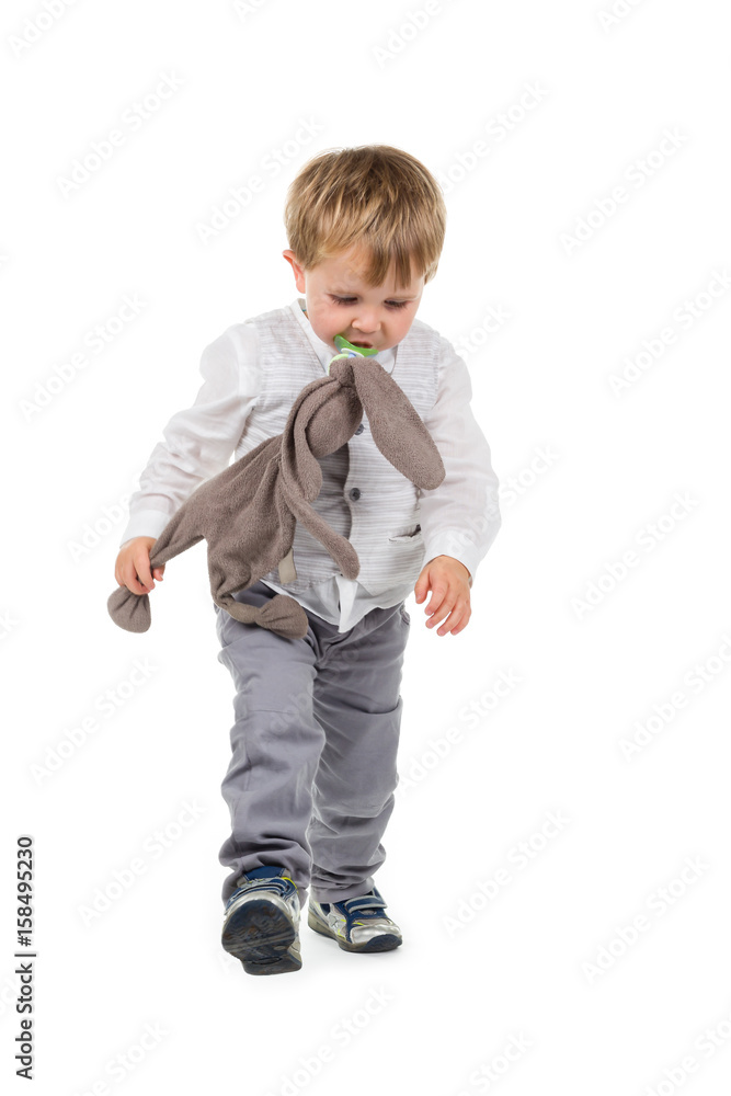 Toddler (boy) with brown plush animal (rabbit) and pacifier walking. Isolated on white background Toddler (boy) with brown plush animal (rabbit) and pacifier walking. Isolated on white background