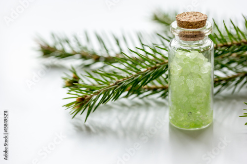 Bottles of sea salt and fir branches for aromatherapy and spa on white table background