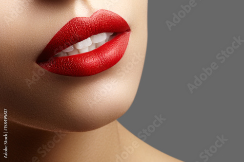 Cosmetics, makeup. Bright lipstick on lips. Closeup of beautiful female mouth with red and pink lip makeup. Part of face