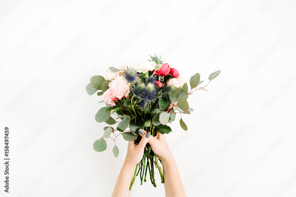 Girl's hands holding beautiful flowers bouquet: bombastic roses, blue eringium, eucalyptus, isolated on white background. Flat lay, top view. Floral composition