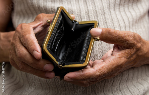 An elderly man holds an empty purse. The concept of poverty in retirement .