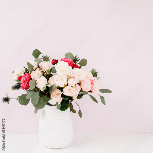 Beautiful flowers bouquet in flowerpot in front of pale pastel pink wall. Floral lifestyle composition.