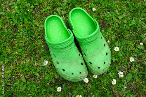Green garden shoes on a spring meadow 
