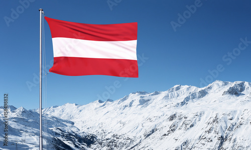 Fotografie The Austrian flag flying from a metal pole in front of the Oztal Alps in Obergur