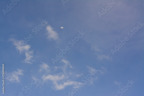 A half moon on clouds and blue sky background.