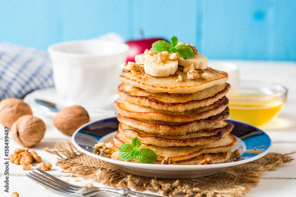 Pancakes with banana, honey, walnuts and mint on plate. Pancakes with banana, honey, walnuts and mint on plate.