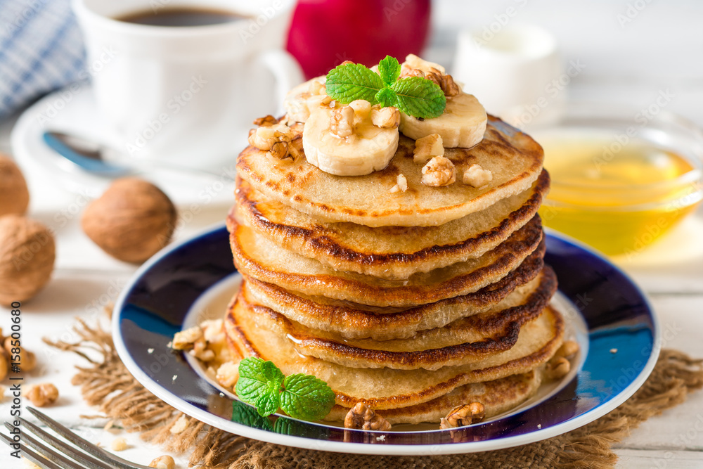 Pancakes with banana, honey, walnuts and mint on plate. Pancakes with banana, honey, walnuts and mint on plate.