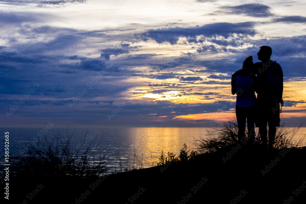 Romantic couple watching a sunset on the cliffs at Pelican Cover