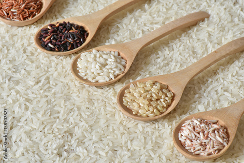 Top view different rice on wooden scoop with jasmine rice background