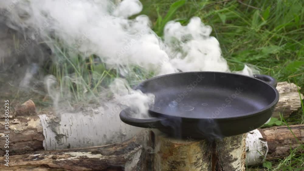 Pan on burning Finnish candle. Preparing food on campfire in wild camping. Pan on burning Finnish candle. Preparing food on campfire in wild camping.