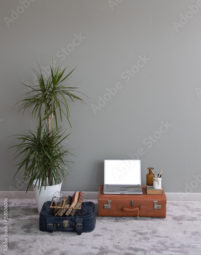 grey wall background vase of flowers and computer on the baggage concept