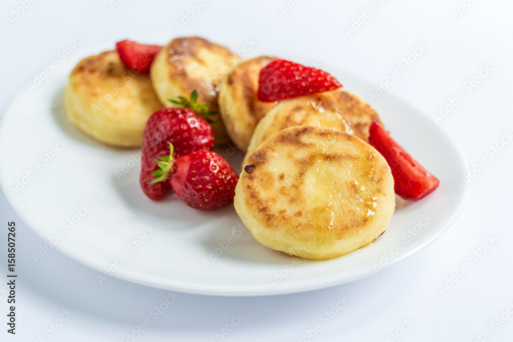 Delicious curd fritters with strawberry on a white plate Delicious curd fritters with strawberry on a white plate