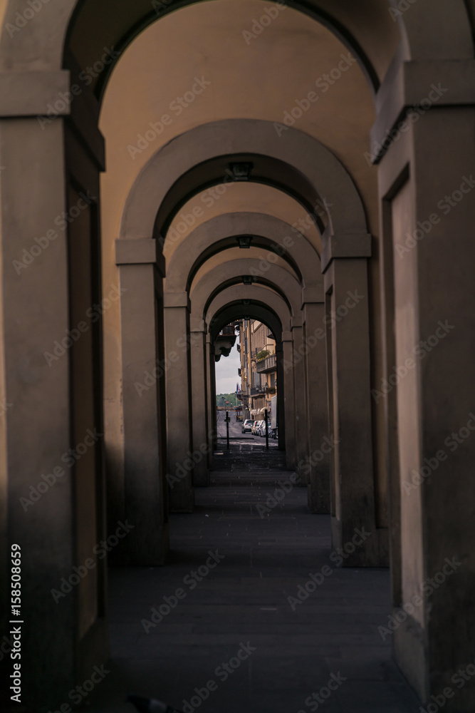 Series of arches along the Arno River in Florence with keyholed street scene.
