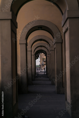 Series of arches along the Arno River in Florence with keyholed street scene. © Chris
