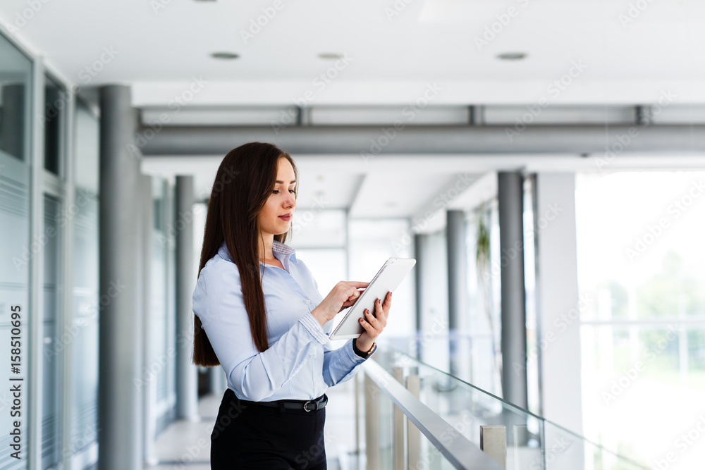 Fototapeta premium Business woman standing and typing on her tablet