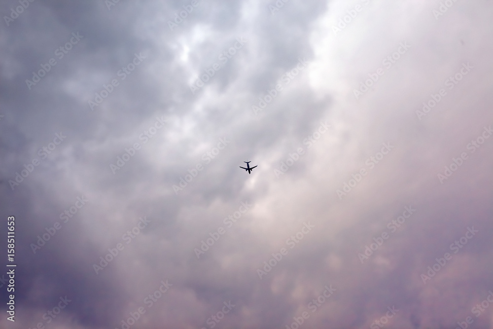 plane flying away in cloudy sky
