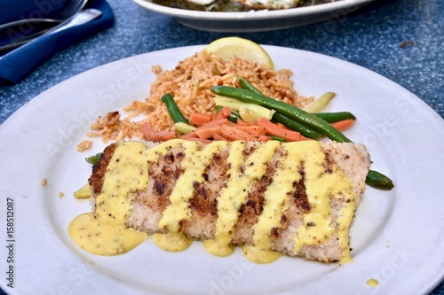 Grilled mahi-mahi drizzled with creamy sauce served with a side of rice and mixed vegetables © Jeramey Lende