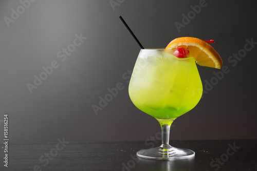 Refreshing Cool Green Alcoholic Drink in a Restaurant Bar with Maraschino Cherry Orange Garnish, Midori Cocktail Snifter Glass