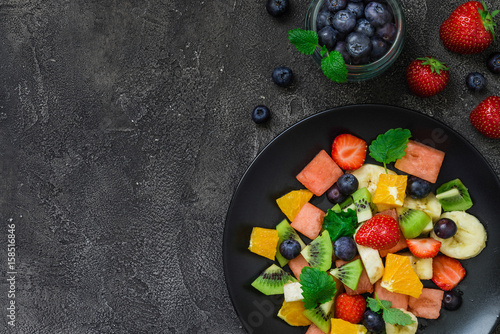 Fresh fruit salad on dark background. Top view, copy space