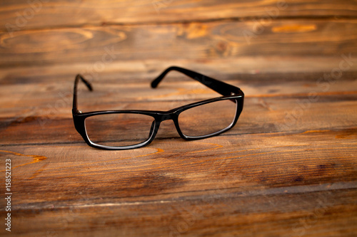 Glasses in black vintage frame on wooden background, table. View from above