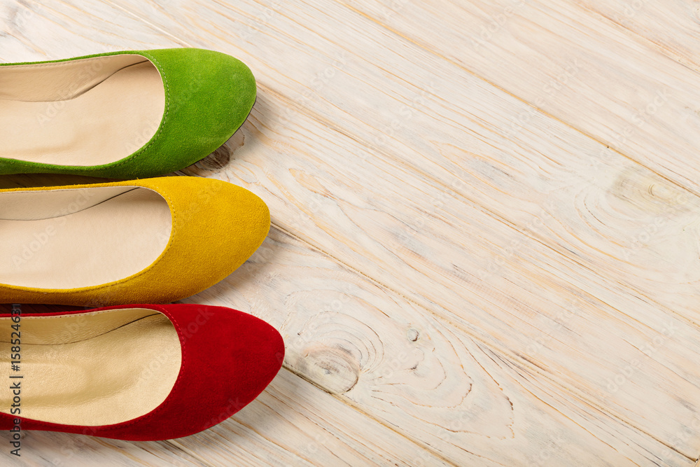 Red, green and yellow women's shoes (ballerinas) on wooden background.