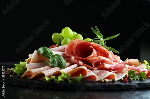 Food tray with delicious salami  pieces of sliced ham  sausage  tomatoes  salad and vegetable - Meat platter with selection