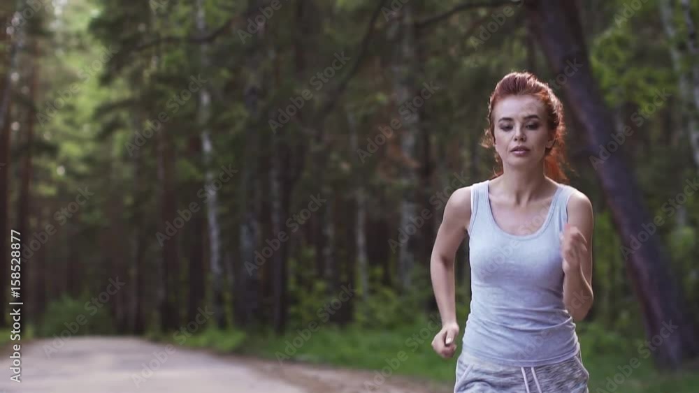 beautiful red-haired girl Jogging in the forest. attractive girl do sport outdoor. slow motion beautiful red-haired girl Jogging in the forest. attractive girl do sport outdoor. slow motion